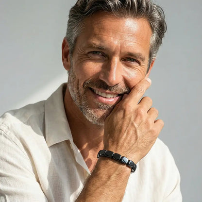 Glimlachende man met grijs haar en baard draagt de zwarte armband om zijn pols, close-up portret