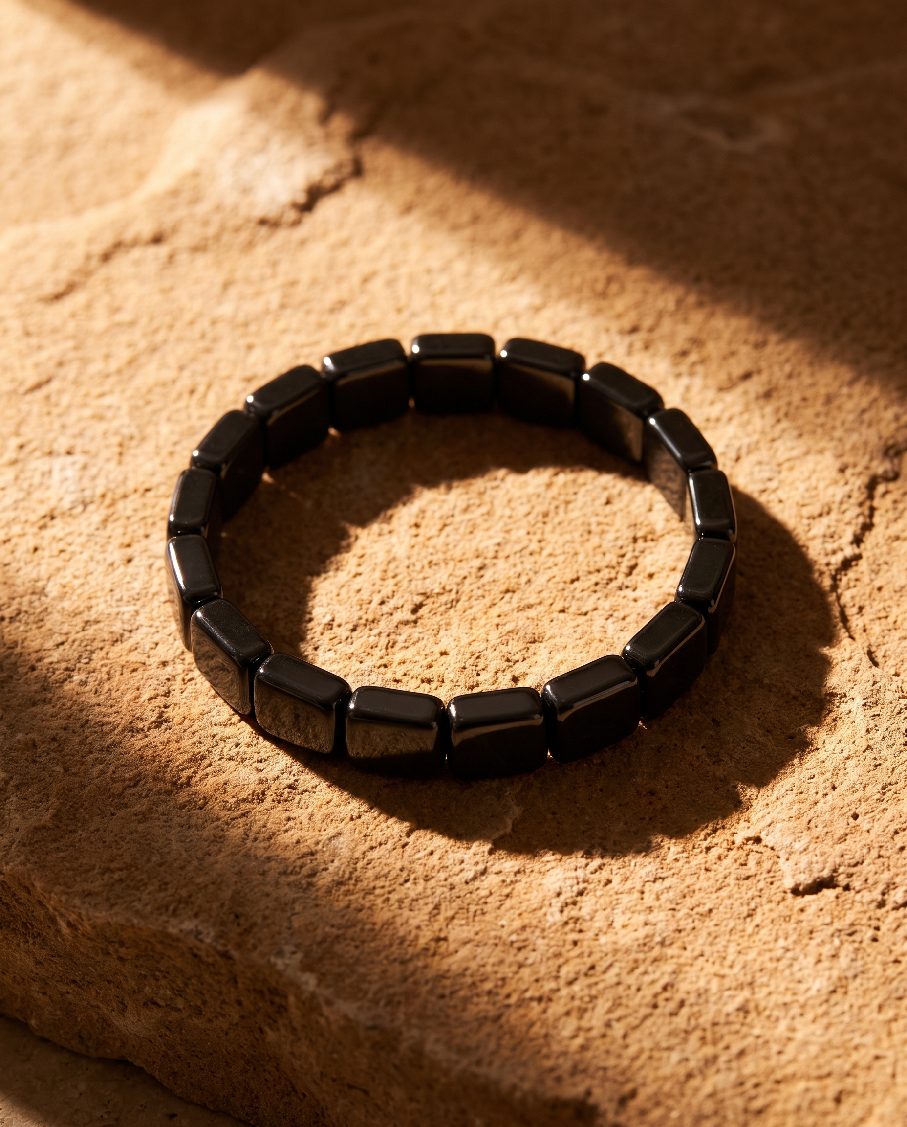 AurumStone Balans en Stijl Armband op warme zandsteen ondergrond met dramatisch zonlicht, catalogusfoto
