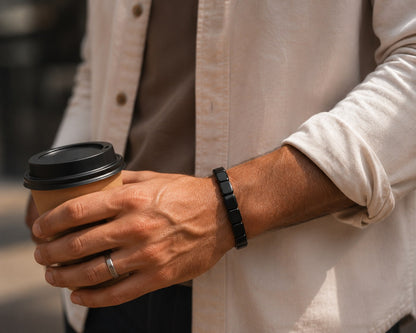 Man met AurumStone armband om de pols houdt een koffiebeker vast op straat, casual lifestyle-shot