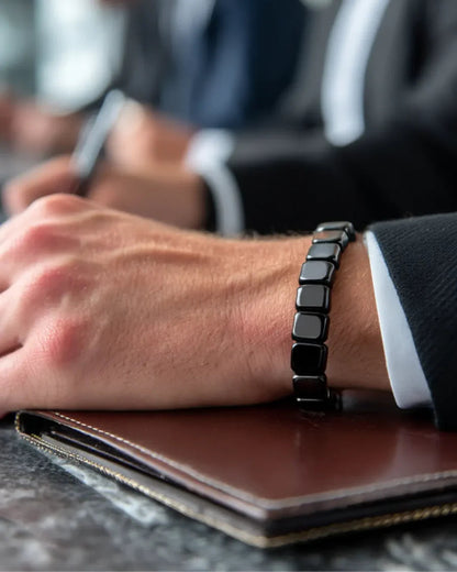 Man in pak met zwarte armband om de pols, hand rustend op een leren notitiemap tijdens een vergadering