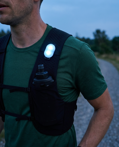 Hardloper draagt Glowdash vest bij schemering met correct wit-blauw gloeiend LED-lampje